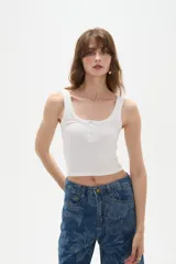 Musculosa blanca de bretel ancho con cuello profundo y cierre frontal con broches.