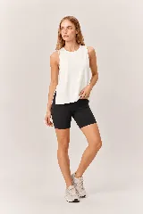 Conjunto deportivo de mujer compuesto por una musculosa blanca de cuello redondo con aberturas laterales y unos shorts biker negros ajustados de tiro alto con bolsillos laterales.