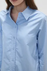 Camisa de algodón blanca, de corte entallado al cuerpo, con cuello camisero, manga larga y cierre frontal de botones.