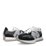 Championes urbanos New Balance modelo 327, con diseño retro inspirado en los años 70. Presentan una combinación de paneles de gamuza negra y malla gris, con el logo 'N' sobredimensionado en color gris claro en el lateral. Incluyen cordones blancos, entresuela de espuma blanca y suela de goma con relieve extendido hacia el talón.