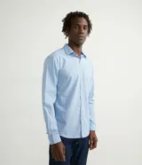 Camisa de manga larga con estampado cuadrillé en tonos celestes y blancos, confeccionada en tejido plano de algodón. Presenta cuello solapa y cierre frontal con botones.