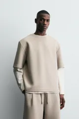 Sudadera de corte oversize confeccionada en tejido técnico de algodón con elasticidad, cuello redondo y manga corta. Presenta una tacha metálica decorativa en la parte posterior.