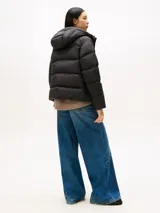 Campera acolchada tipo puffer de Tommy Hilfiger, color negro, con relleno de plumón, capucha fija, cierre frontal con cremallera oculta y botones a presión, y logo tonal bordado en el pecho.