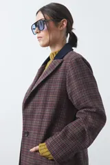 Blazer de corte relajado con estampado de cuadros tipo pied de poule en tonos rojizos y verdes. Presenta solapas clásicas en color azul oscuro y estructura definida.