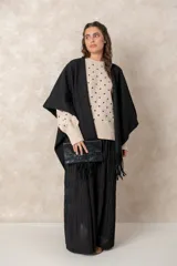 Ruana abierta de color beige, confeccionada en tejido de punto con terminación de flecos en el ruedo.