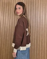 Cardigan de punto color marrón con detalles en tono arena en los bordes de la botonera, cuello en V, dobladillo y puños. Cuenta con cierre frontal de botones.