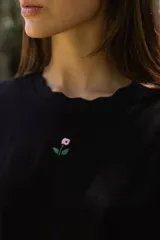 Remerón a rayas horizontales blancas y violetas con cuello redondo con detalle de ondas y bordado de una flor en el pecho.