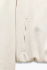 Chaqueta bomber de cuello redondo y manga larga con diseño holgado. Presenta cierre frontal con cremallera, bolsillos delanteros de vivo y acabados elásticos en los puños y el ruedo.