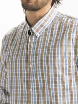 Camisa celeste y blanca a cuadros con cuello abotonado, manga larga y bolsillo en el pecho.