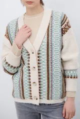 Cardigan de punto con escote en V y cierre frontal de botones. Presenta un diseño estampado con patrones geométricos en tonos beige, marrón y detalles en azul vibrante.
