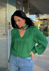 Blusa de satén color verde, con cuello en V y detalle de lazo integrado al cuello. Presenta mangas largas abullonadas con puños ajustados.