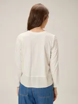 Remera de manga larga en color marrón, confeccionada en una combinación de tejido de punto y tela plana. Presenta un diseño de superposición frontal con costura decorativa en contraste y un panel inferior de textura diferenciada.