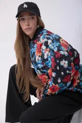 Campera bomber acolchada con cierre frontal, diseño estampado floral multicolor sobre base negra, cuello, puños y ruedo elásticos.