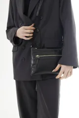 Bandolera de cuero negro, de diseño rectangular y compacto, con correa ajustable para llevar cruzada al hombro. Cuenta con un bolsillo frontal con cierre y detalles de costuras pespuntadas a contratono.