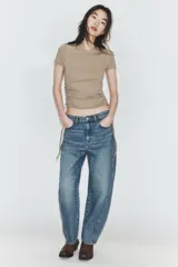 Camiseta corta de cuello redondo y manga corta, color gris oscuro, con frunces laterales ajustables mediante cordones.