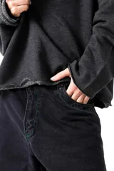 Buzo gris oscuro, estilo sweatshirt, con cuello redondo y terminaciones al corte en cuello, puños y cintura. Presenta un bordado en el frente.