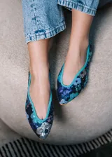 Bailarina de punta redonda con exterior cubierto de lentejuelas que forman un diseño floral multicolor sobre base azul marino. Presenta un ribete en color turquesa y suela plana de cuero.