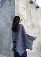 Poncho de hilo liviano en color azul jaspeado, con diseño sin cuello y caída fluida. Es una prenda versátil de talle único, ideal para usar como capa sobre otras prendas durante la media estación.