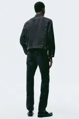 Jean de cinco bolsillos en denim de algodón rígido, color negro con efecto deslavado. Modelo con pierna recta y corte estándar de cintura a bajo, con cierre de botones.