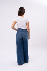 Pantalón de jean corte wide leg con costura central vertical, tiro medio y cierre frontal con botones.