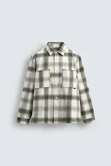 Camisa de corte relajado confeccionada en tejido de algodón con acabado de franela. Presenta cuello solapa, cierre frontal de botones, manga larga con puños abotonados y dos bolsillos de plastrón en el pecho.