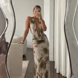 Vestido largo de microtul con estampado tie-dye en tonos beige y verde militar, escote halter pronunciado y espalda descubierta con tiras regulables.