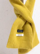 Bufanda de tejido de punto en color amarillo mostaza, confeccionada en lana, con etiqueta de marca visible.