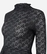 Blusa de encaje floral negro con cuello alto y mangas largas. Presenta un diseño ajustado en el torso con un detalle peplum en el ruedo que aporta volumen y movimiento.