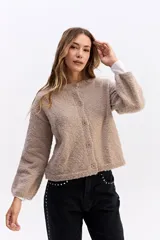 Saco de punto con textura tipo bouclé, de calce relajado y diseño levemente cropped. Cuenta con cuello redondo y cierre frontal mediante botones.
