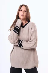 Sweater de punto color marrón con cuello redondo, puños y cuello con detalles de rayas blancas en contraste. De corte holgado y manga larga.