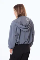 Campera corta impermeable con capucha, cierre frontal completo y puños elásticos.