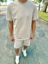 Conjunto deportivo beige compuesto por una remera de manga corta con cuello redondo y un short a juego con cordón ajustable.