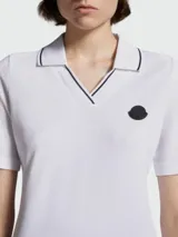 Remera polo de algodón blanca con cuello en V y detalles de líneas finas en contraste. Presenta mangas cortas y el logo de la marca aplicado en el pecho.