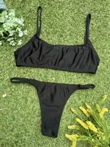 Conjunto de bikini negro con corpiño tipo top y bombacha colaless regulable, confeccionado en tela metalizada.