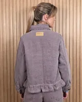 Sobrecamisa de pana color gris con diseño a rayas diagonales sutiles, cuello camisero, cierre frontal con botones, bolsillos aplicados al frente y detalle de volado en el ruedo.