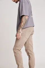 Pantalón de jean color beige, corte slim fit, con bolsillos delanteros y traseros.