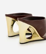 Sandalias tipo mule de color marrón, con tiras anchas en el empeine, tira fina separadora de dedos, puntera cuadrada y taco chino calado con acabado dorado metalizado.