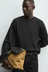 Sudadera de cuello redondo y manga larga, confeccionada en tejido de algodón pesado con interior de rizo ligeramente afelpado. Presenta un corte relajado y acabados en rib en puños y ruedo.