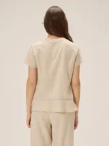 Camisa de manga corta color beige con estampado a cuadros, cuello en V y detalles de galones decorativos estilo oriental en la parte frontal.