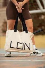 Bolso tipo tote bag de algodón color crudo, con asas negras y estampado frontal con la palabra "LON" en letras negras grandes.