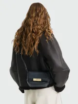 Cartera cruzada Longchamp modelo Le Smart Flow S, confeccionada en cuero texturizado negro, con solapa frontal y cierre metálico dorado. Cuenta con correa fina ajustable para llevar al hombro o cruzada.