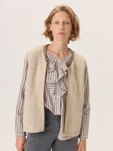 Chaleco de tejido de punto con textura en relieve, color beige, con cierre frontal y bolsillos laterales. Diseño sin mangas con cuello redondo.