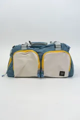 Bolso de viaje azul con detalles en amarillo, blanco y gris.