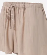 Short de playa color beige, confeccionado en viscosa y poliamida, con diseño holgado, bolsillos laterales, cintura elástica con cordón de ajuste tipo lazo y detalle de botones frontales.