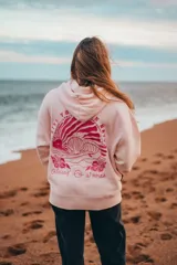 Hoodie rosa con capucha y cordones ajustables. Estampado en la espalda con un diseño de ondas, sol, concha marina y flores de hibisco.