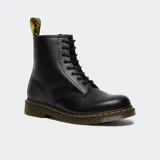 Bota de caña media Dr. Martens modelo 1460, confeccionada en cuero marrón con acabado mate. Presenta cierre de cordones con ocho ojales metálicos, costuras amarillas características en la unión de la suela y suela de goma acanalada con amortiguación de aire.