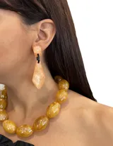 Aros colgantes color salmón con forma geométrica irregular y detalles en negro.