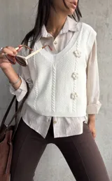 Chaleco tejido color natural con escote en V, diseño de trenzas y flores en relieve.