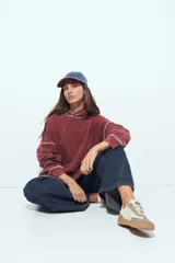 Buzo con capucha de calce relajado, con efecto lavado y costuras a la vista en contraste. Presenta mangas largas y bolsillo frontal tipo canguro.