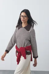 Sweater de punto a rayas horizontales en color bordó y celeste, con cuello polo y mangas largas con puños amplios. Presenta un diseño de calce relajado.